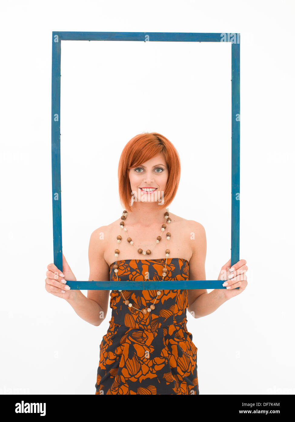 Caucasian woman holding un cadre vide en face d'elle, sur fond blanc Banque D'Images