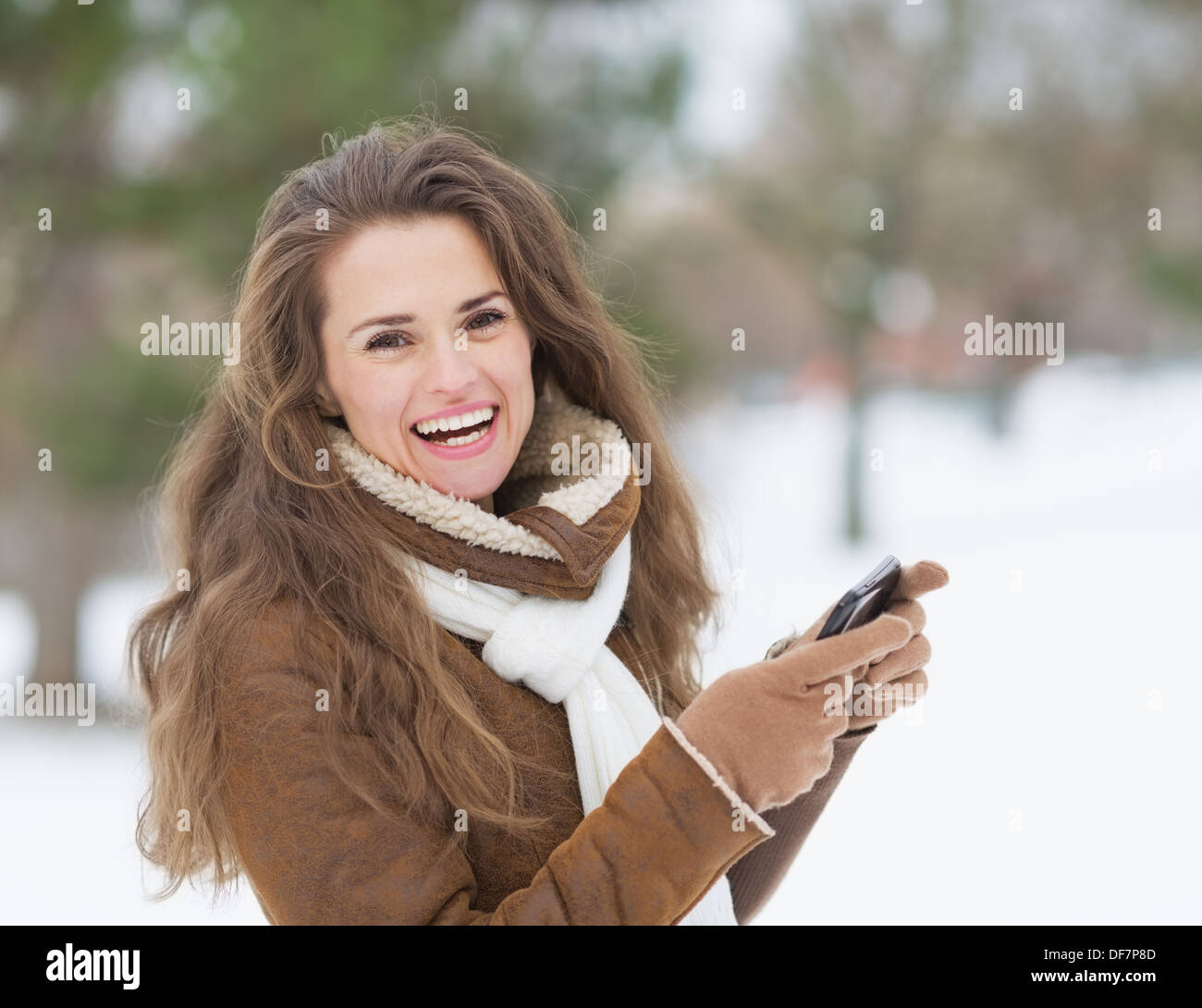 Smiling young woman with cell phone en hiver en plein air Banque D'Images
