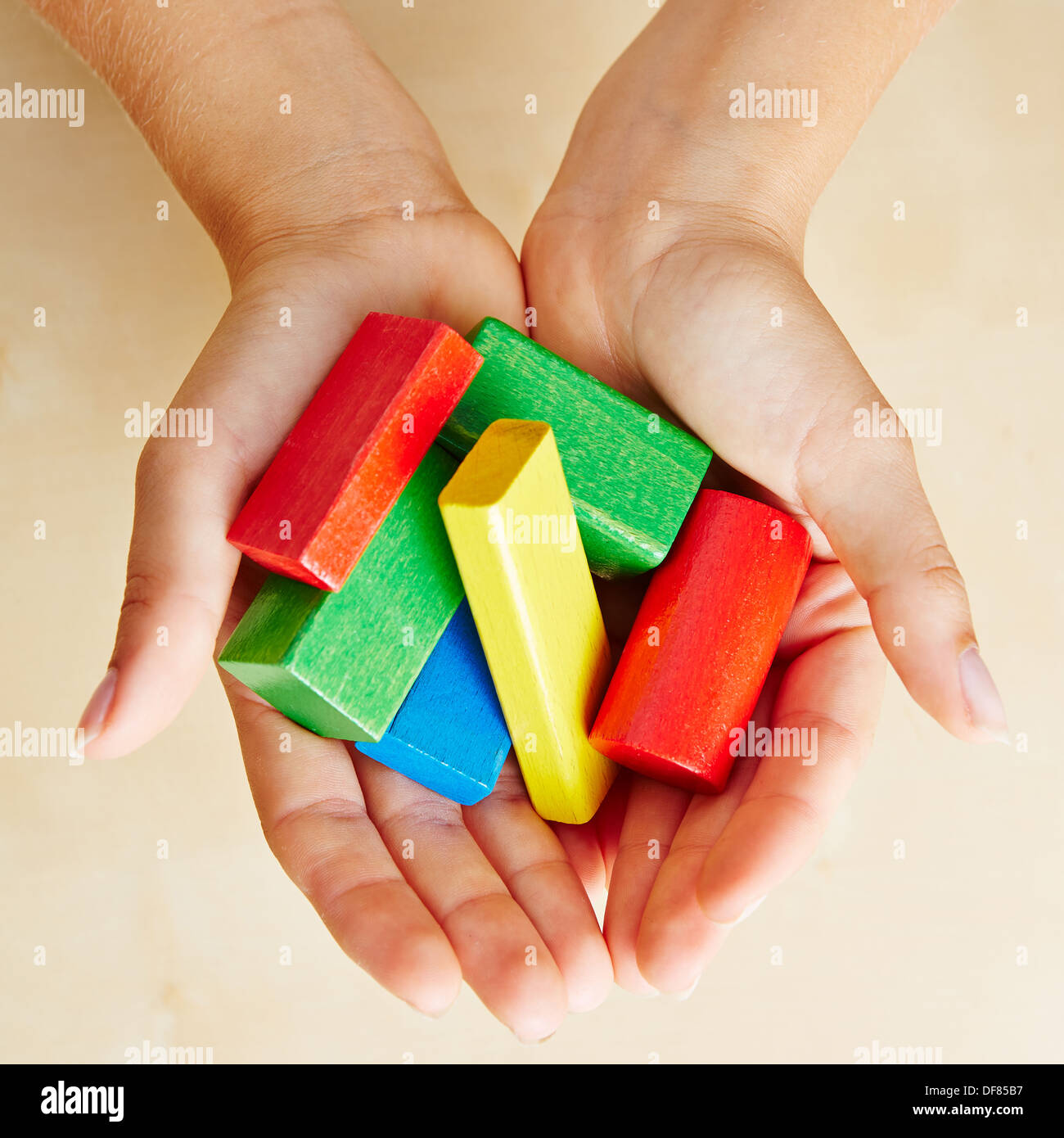 Deux mains au-dessus de la tenue des briques de bâtiment coloré Banque D'Images