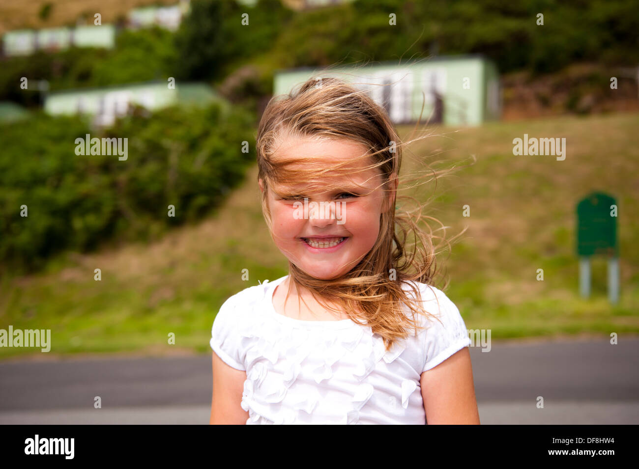 Girl au caravan park avec grand sourire à windswept Banque D'Images