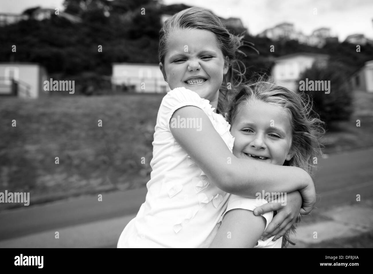 Avec les filles en souriant à pleines dents hugging noir et blanc Banque D'Images