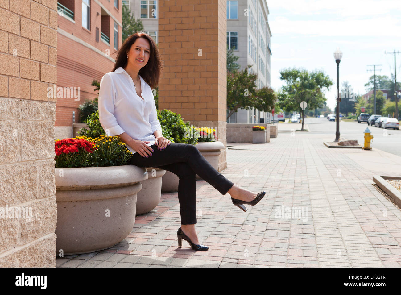 Middle aged woman sitting in front of building Banque D'Images