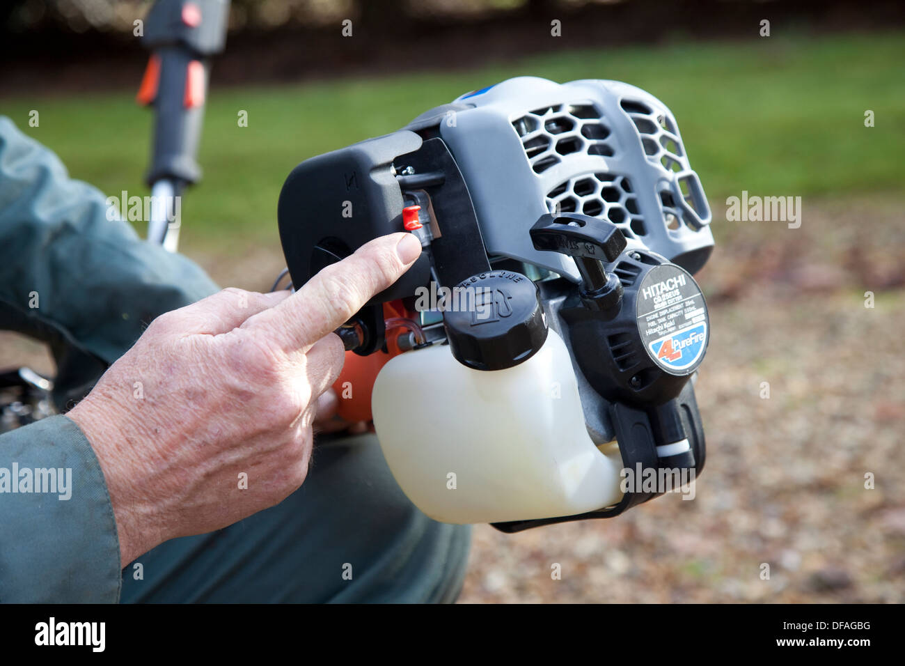 Un homme montre le moteur à essence d'un strimmer UK Banque D'Images