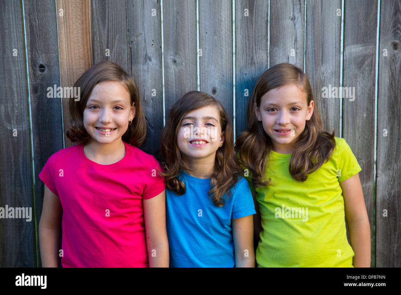 Soeur et amis kid filles portrait smiling happy sur bois jardin clôture gris Banque D'Images
