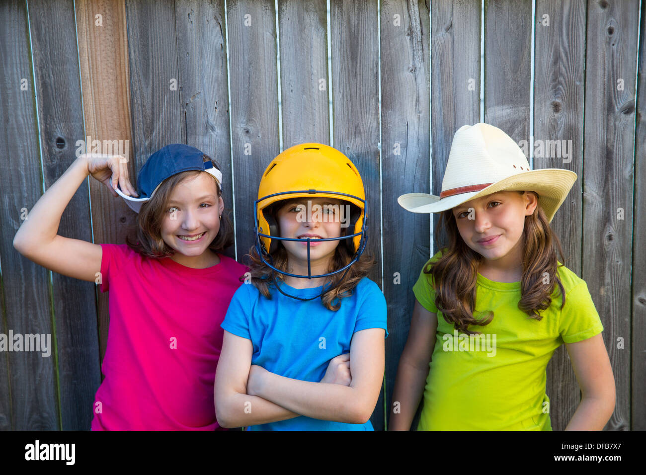 Soeur et ses amis pour enfants sport girls smiling happy portrait sur bois jardin clôture gris Banque D'Images