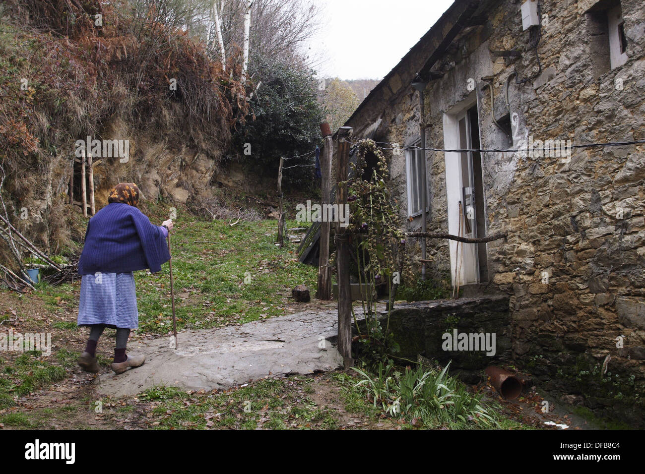 Vieille Femme entrer dans sa maison dans la Serra do Courel après collecte  du bois de feu pour l'hiver. Remarque La sabots en bois typique Photo Stock  - Alamy