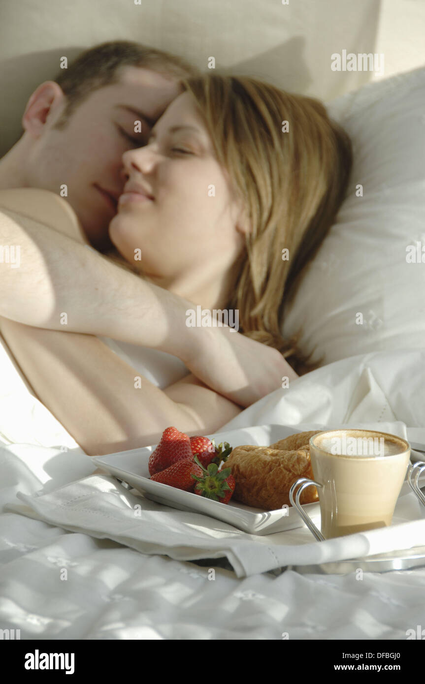 Jeune couple dans le lit de câlins avec le bac d'aliments pour petit  déjeuner Photo Stock - Alamy