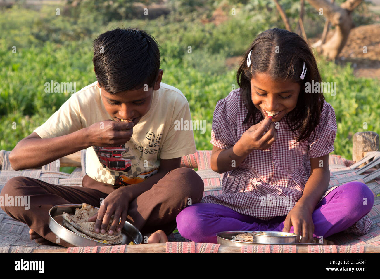 L'Inde, Uttar Pradesh, Agra, frère et soeur de manger le petit déjeuner traditionnel indien de roti et pommes de terre, curry (aloo ghobi) Banque D'Images