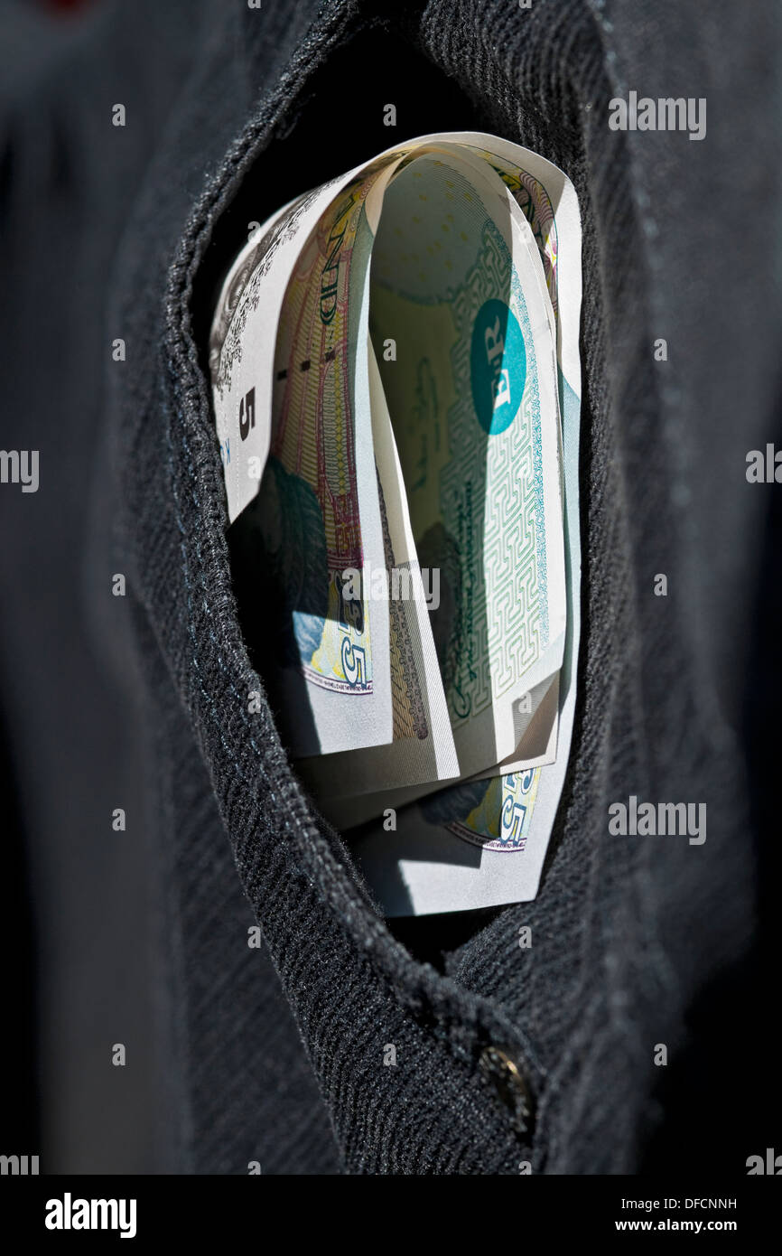 Gros plan des billets de banque anglais pliant de l'argent exposé dans la poche du pantalon menant au concept d'entreprise de pickpocket Angleterre Royaume-Uni Grande-Bretagne Banque D'Images