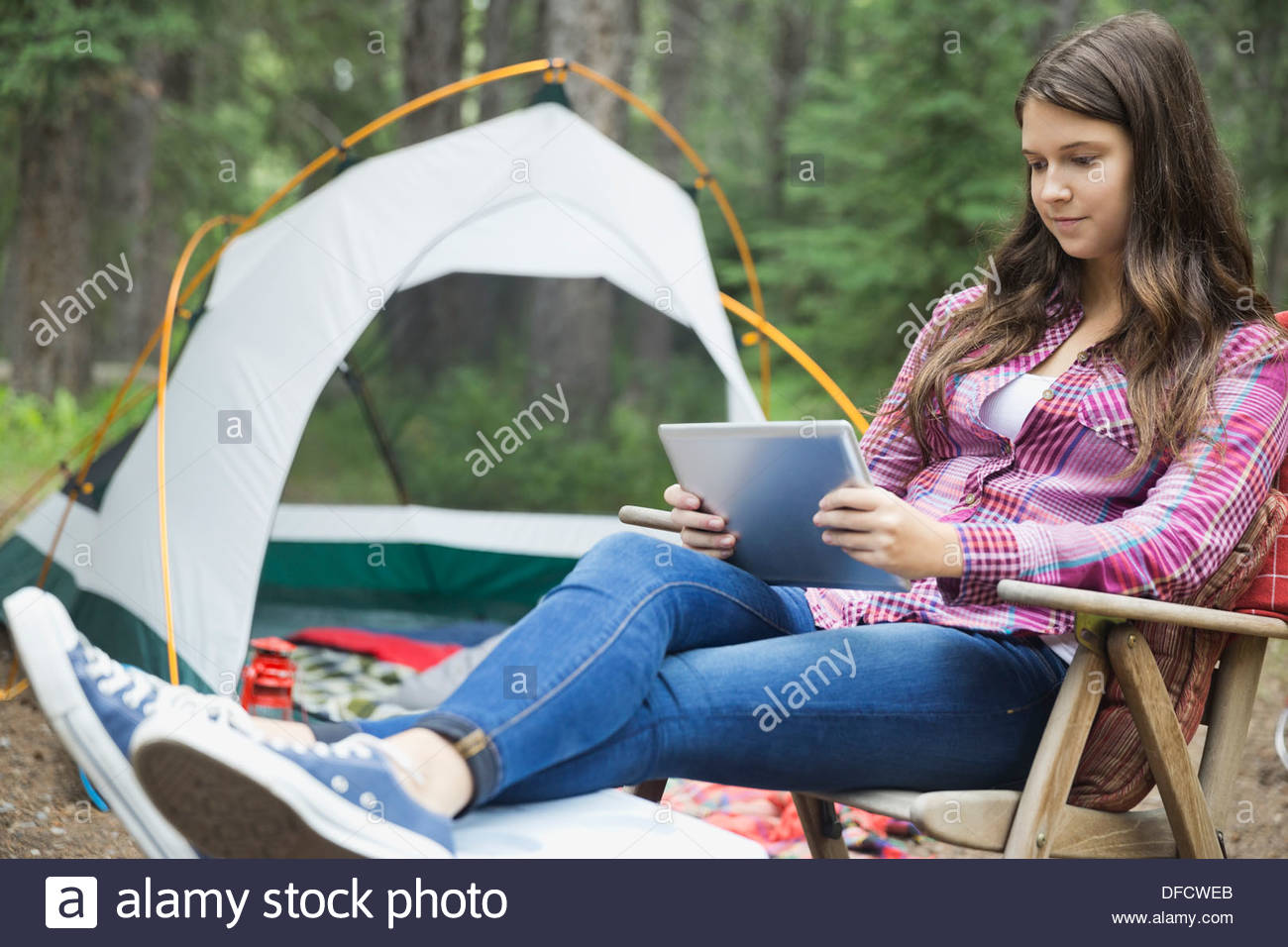 Teenage girl using digital tablet at campsite Banque D'Images