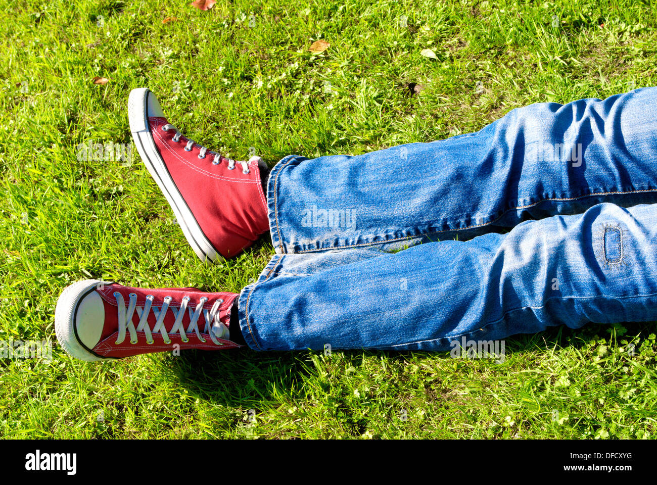Les jambes d'un jeune homme relaxing on grass Banque D'Images