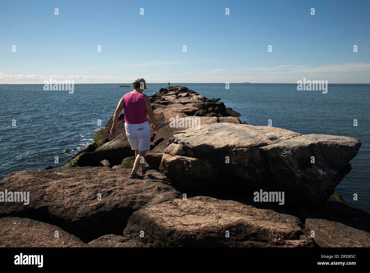 À la fin de l'été, une femme marche le long de la jetée à Hammonasset Beach State Park, Madison, Connecticut. Banque D'Images