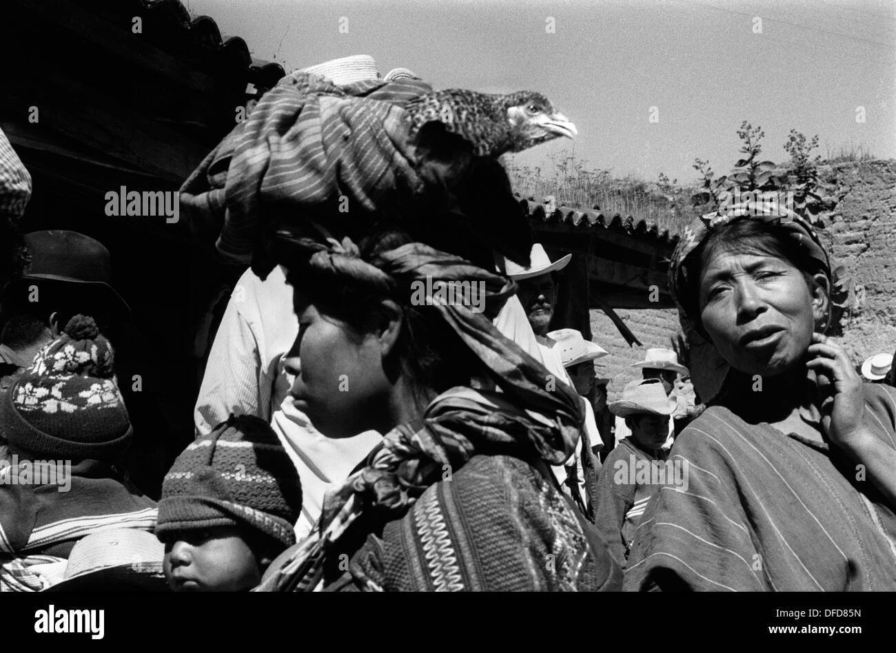 Femme autochtone faisant du shopping dans un marché Chimaltenango, Guatemala.Elle est en costume traditionnel indigène et porte un bébé à travers sa poitrine dans une élingue, et un poulet sur sa tête.Amérique centrale.1973 1970s HOMER SYKES Banque D'Images