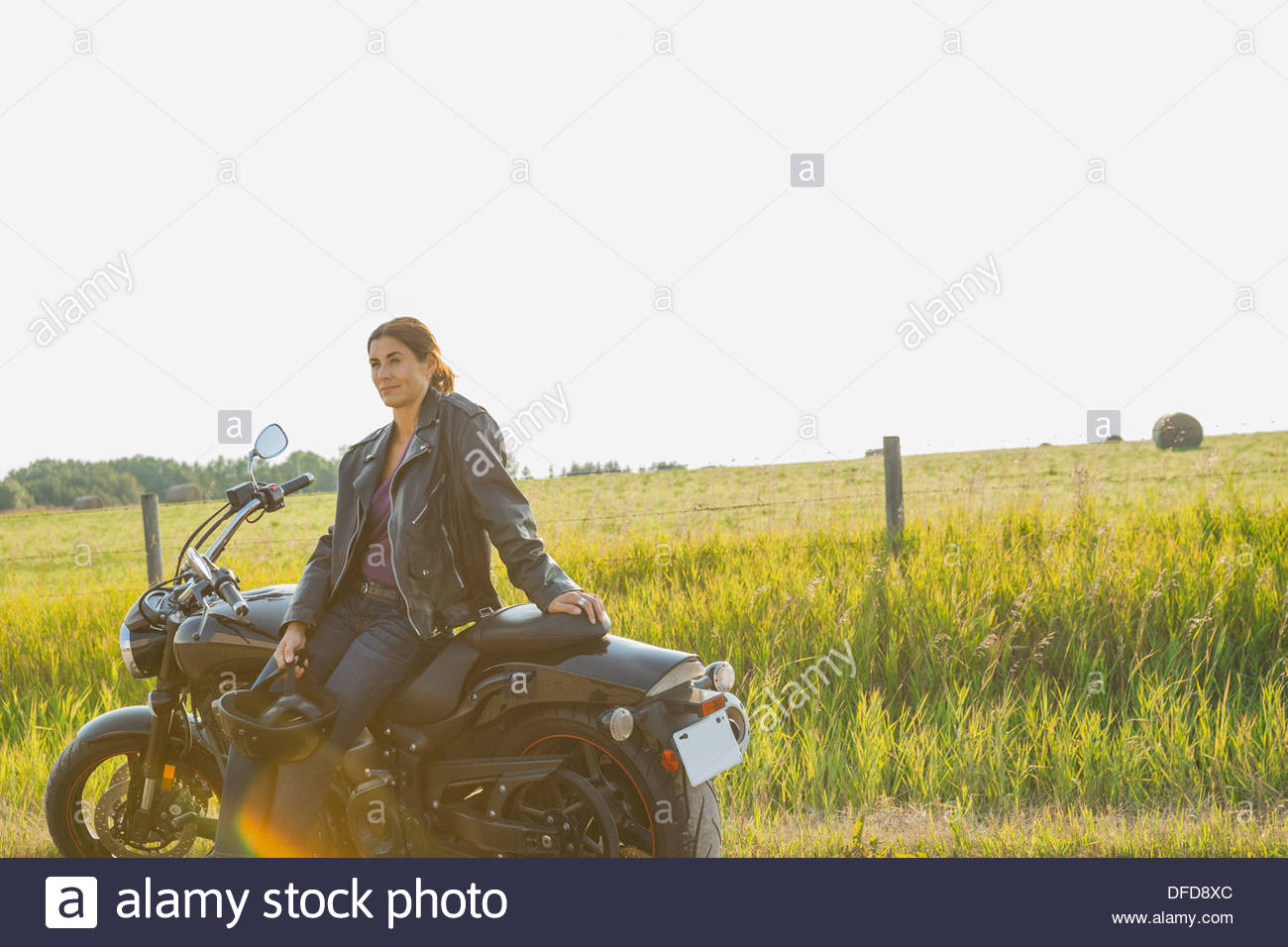 Femme sérieuse biker moto appuyée contre Banque D'Images