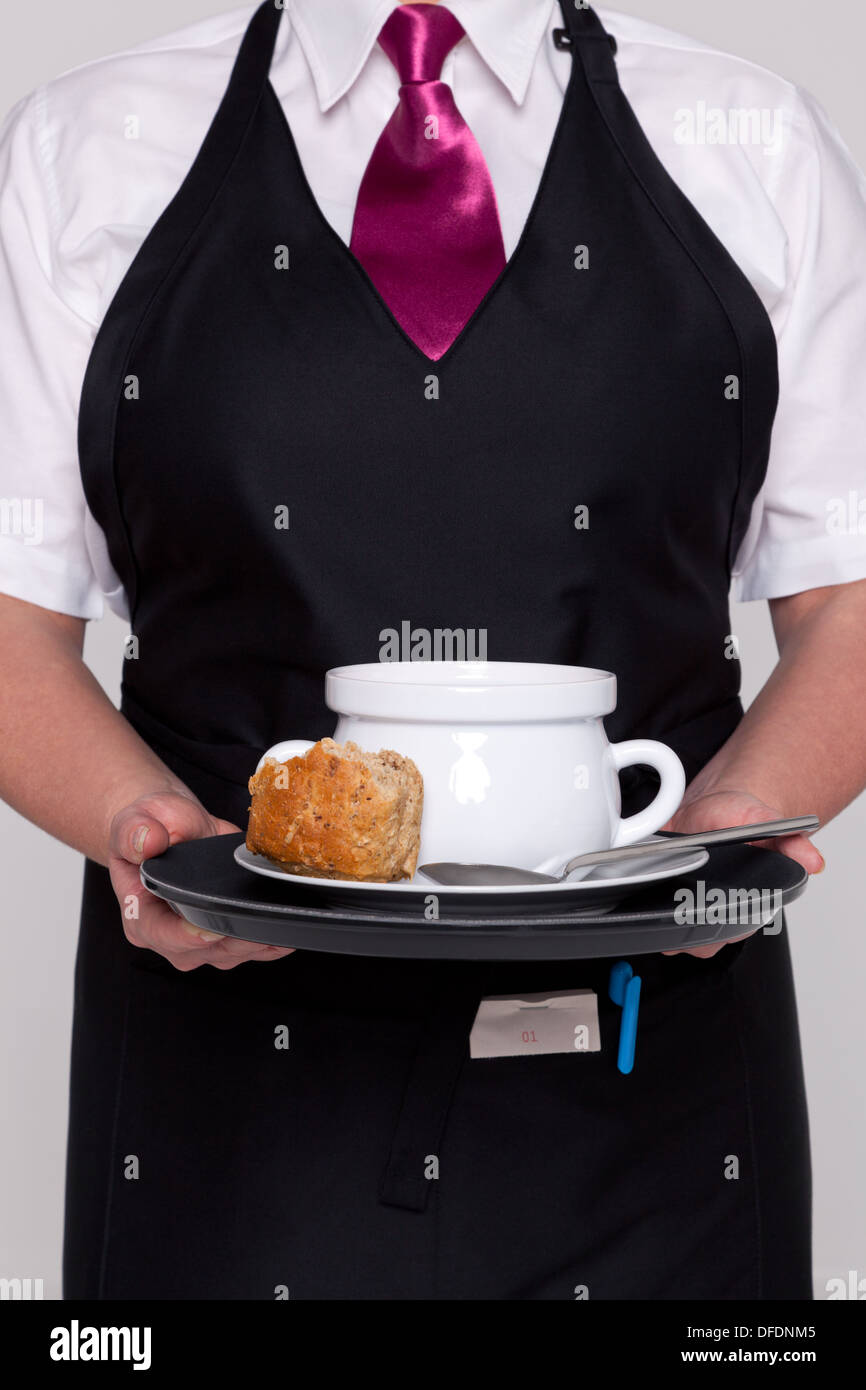 Une serveuse portant un tablier et une cravate de servir un bol de soupe et  de pain frais Photo Stock - Alamy