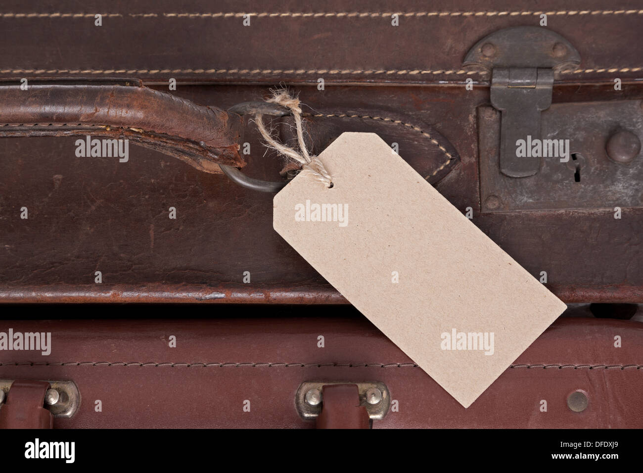Photo d'une étiquette de bagage en blanc sur une vieille valise en cuir marron. Banque D'Images