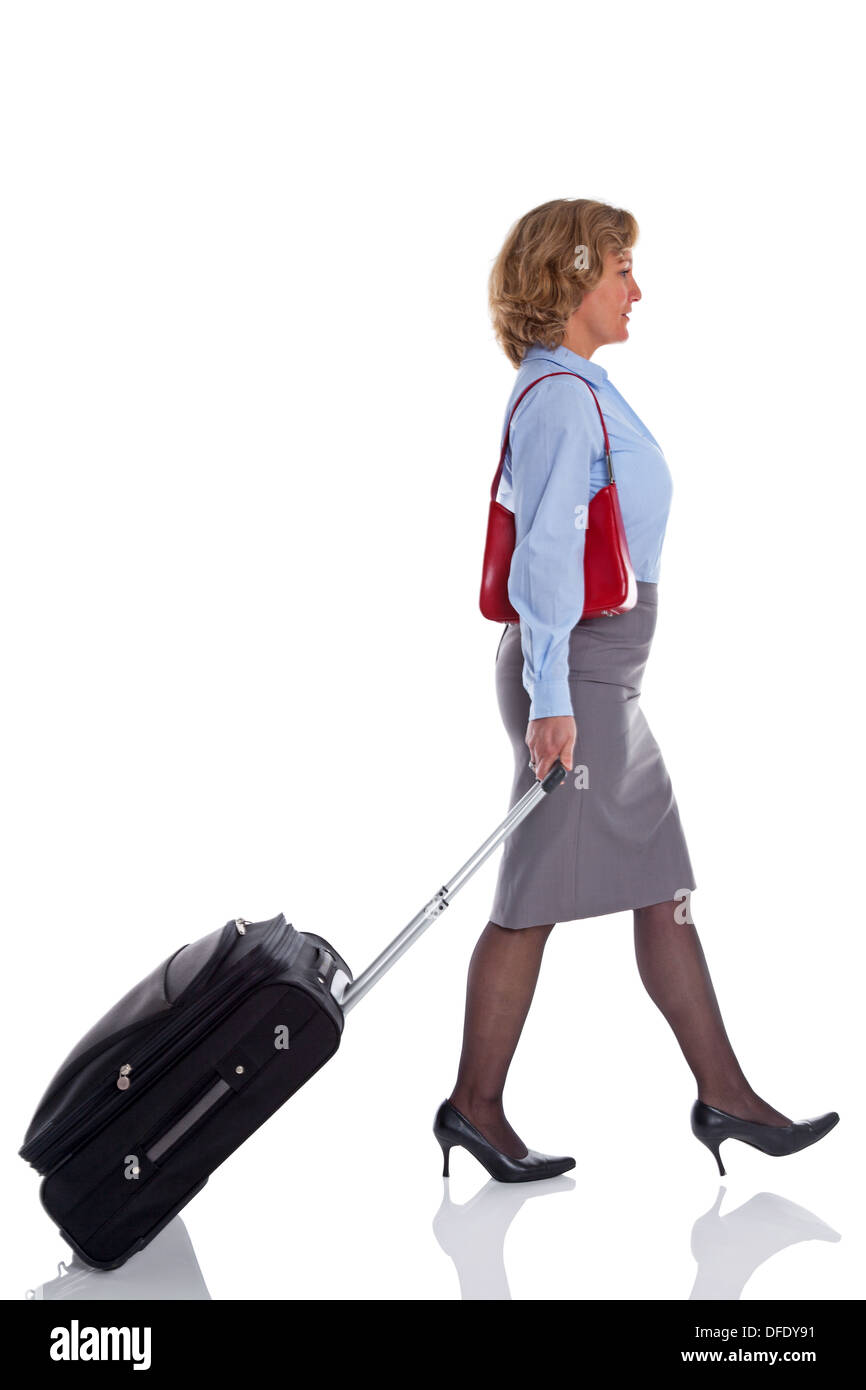 Une femme marchant le long de la traction d'une valise, isolé sur fond blanc. Banque D'Images