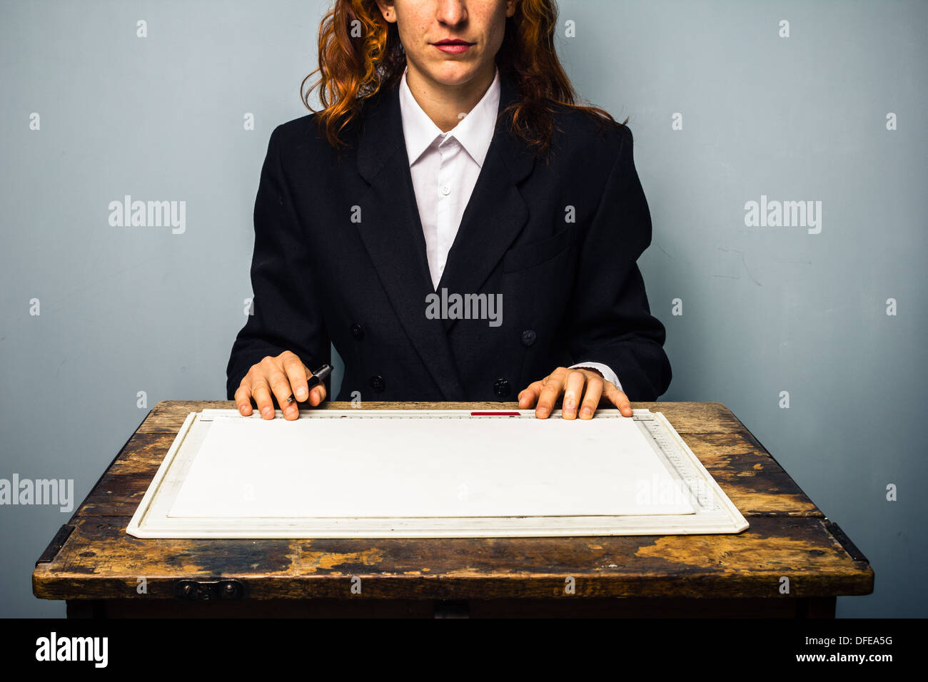 Jeune femme d'affaires assis à un bureau avec table à dessin en face d'elle Banque D'Images