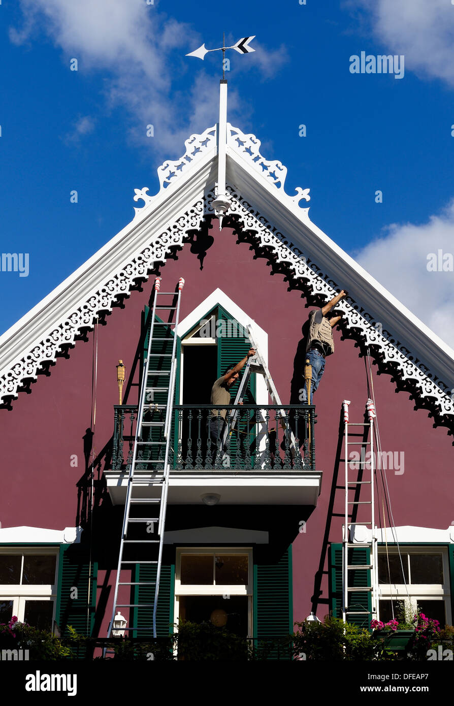 Deux hommes en utilisant des échelles pour re sur le fil d'une maison traditionnelle de Madère Portugal Banque D'Images