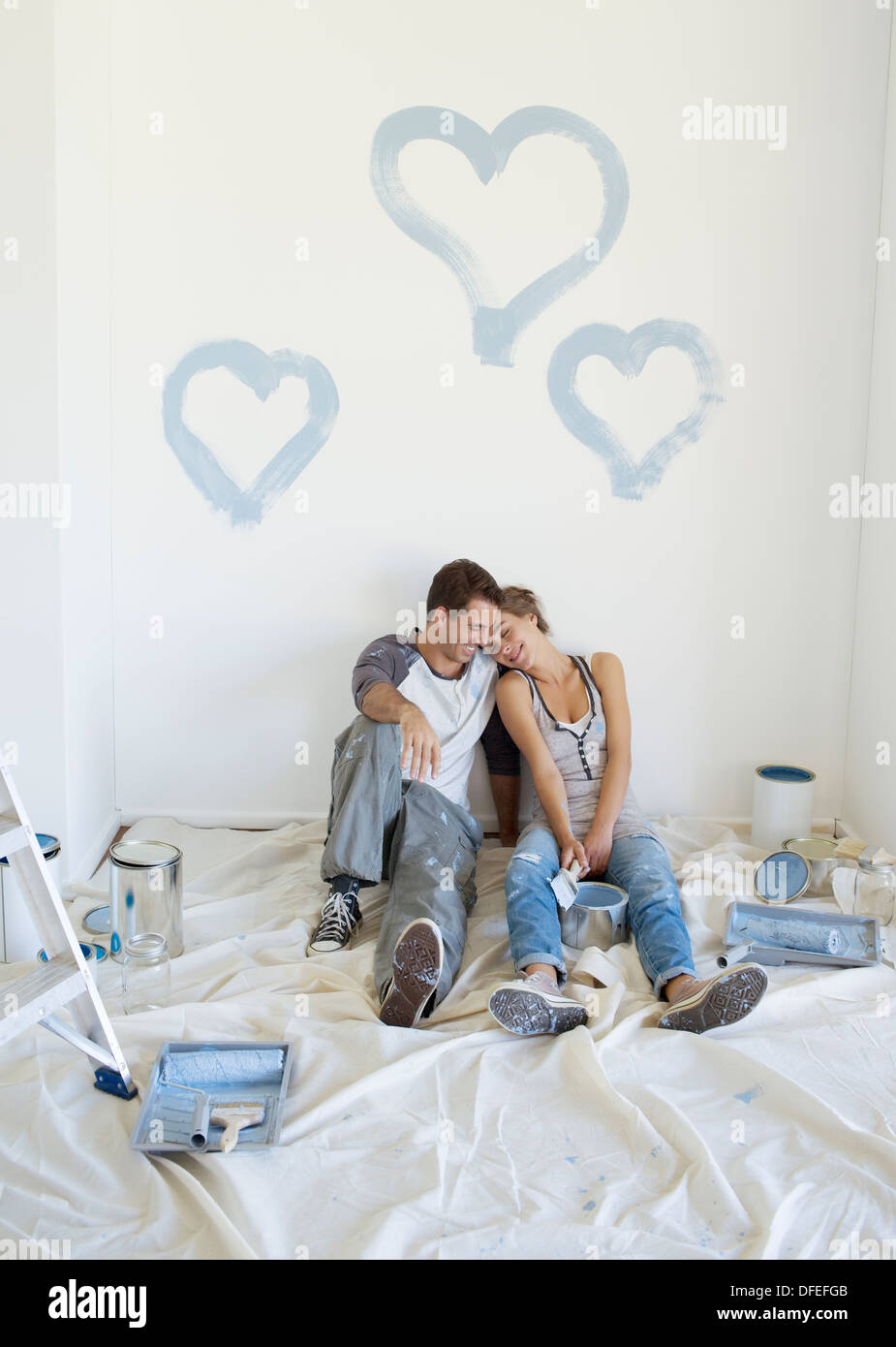 Couple painting blue hearts on wall Banque D'Images