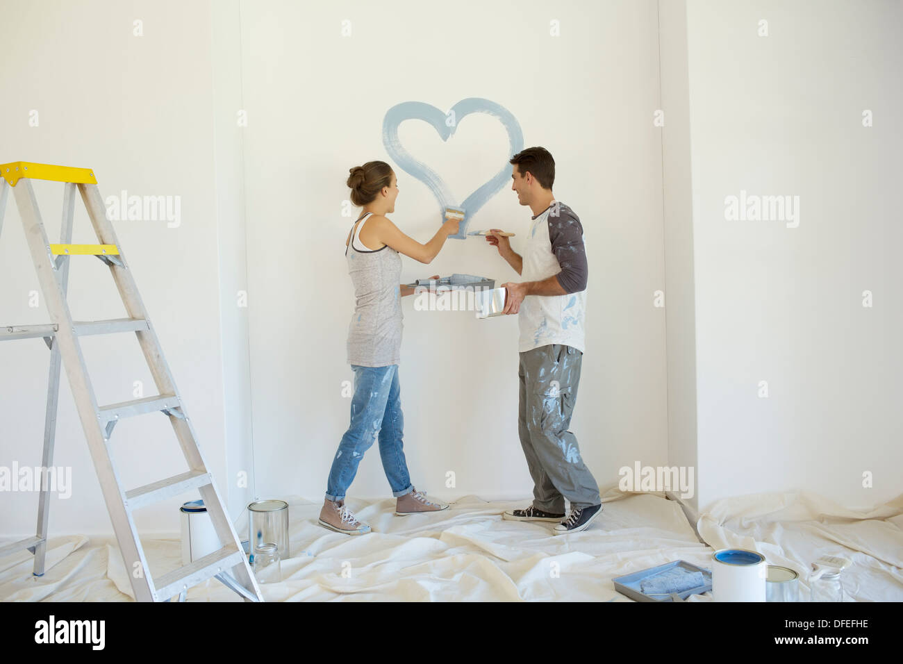 Couple painting blue heart on wall Banque D'Images