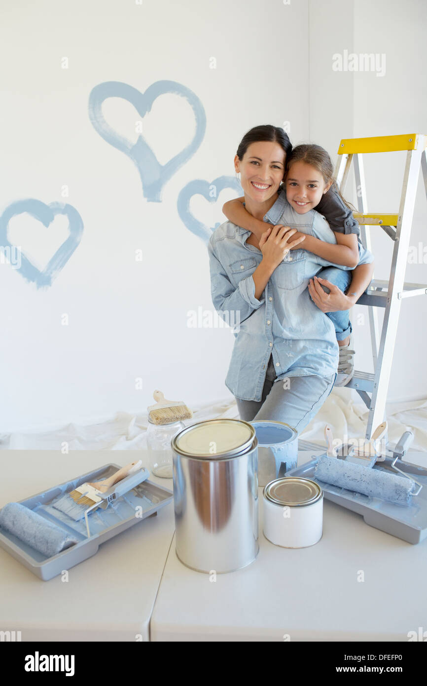 Mother and Daughter hugging parmi les fournitures de peinture Banque D'Images