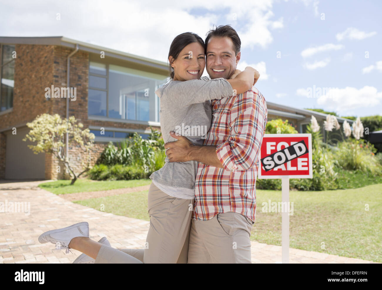 Portrait of smiling couple hugging outside new house Banque D'Images
