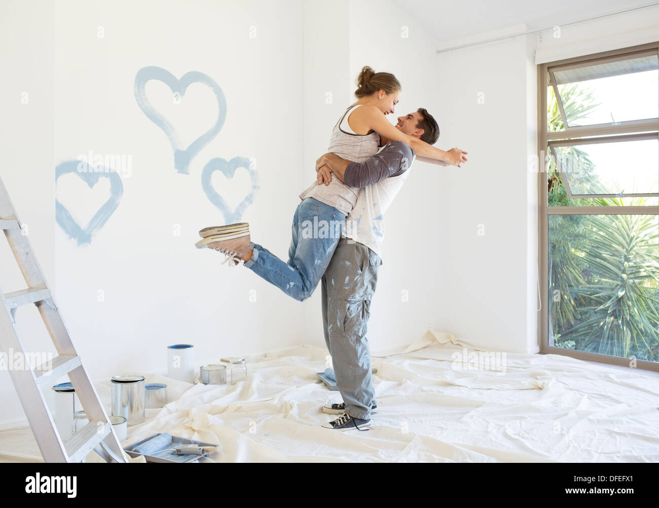 Couple painting blue hearts on wall Banque D'Images