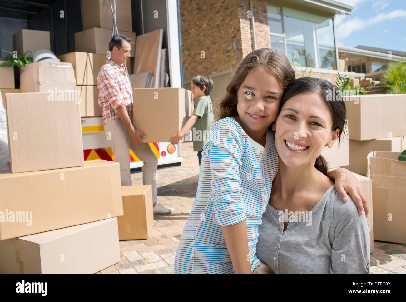 Mère et fille smiling par camion de déménagement dans l'allée Banque D'Images