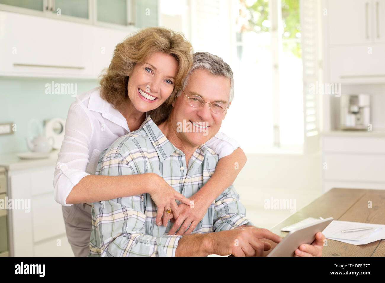 Portrait of smiling senior couple with digital tablet in kitchen Banque D'Images