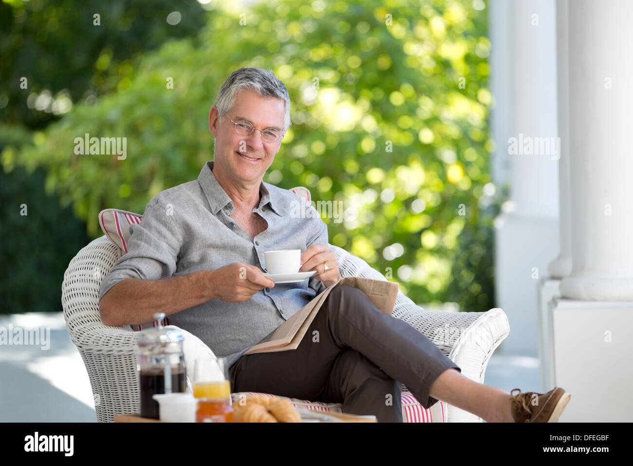 Portrait of smiling senior man drinking coffee on patio Banque D'Images