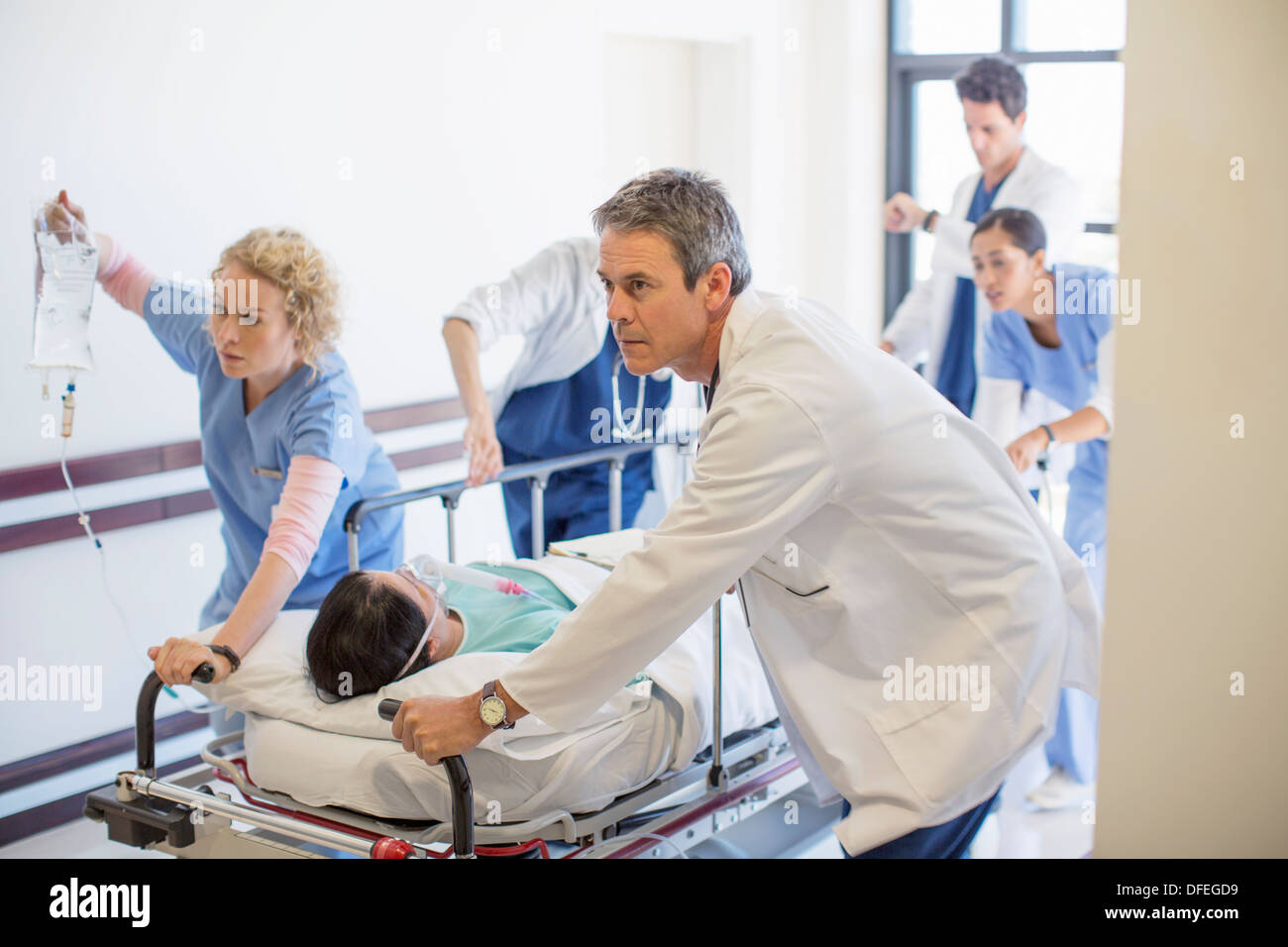 Doctors rushing patient on stretcher down hospital corridor Banque D'Images