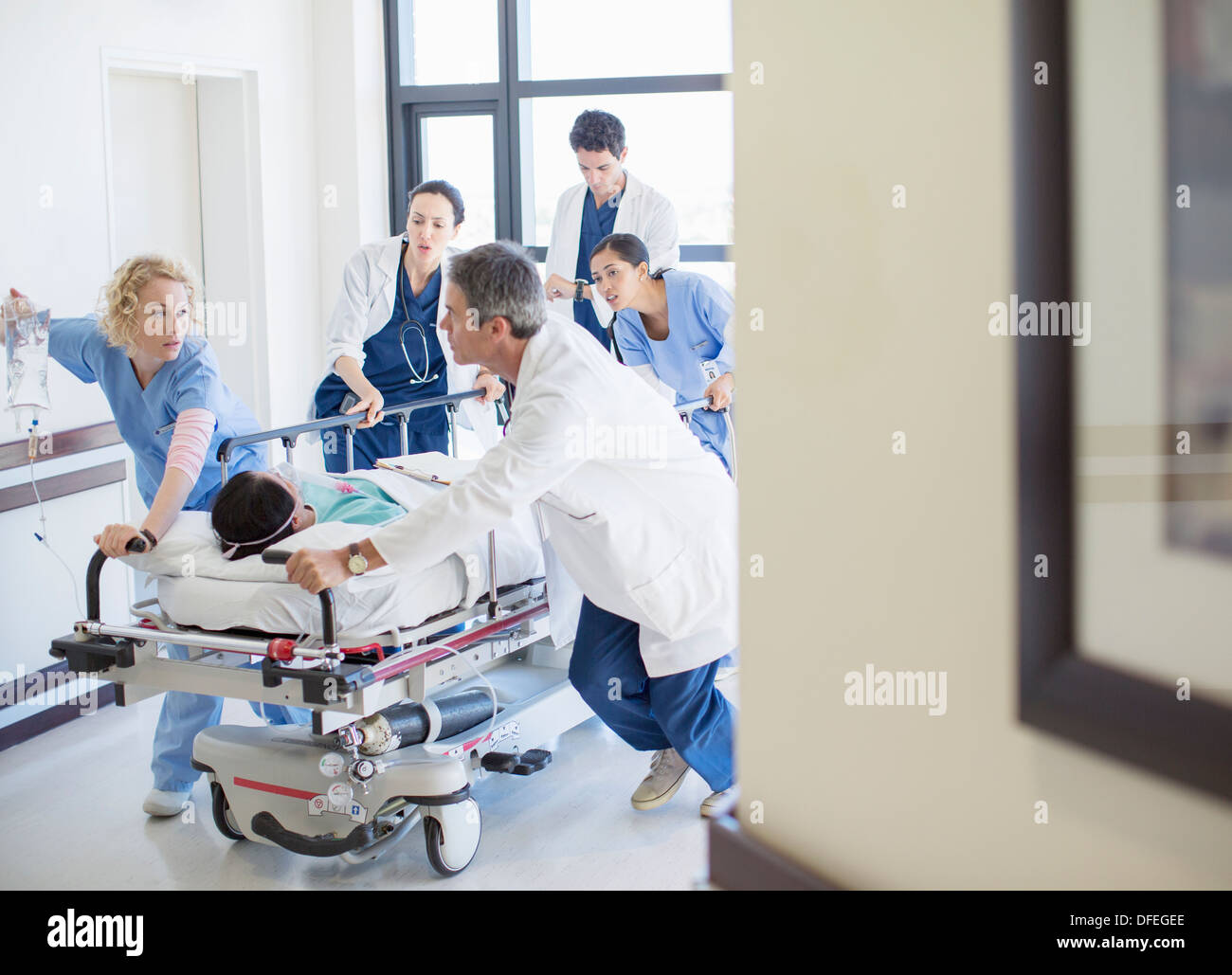 Doctors rushing patient on stretcher down hospital corridor Banque D'Images