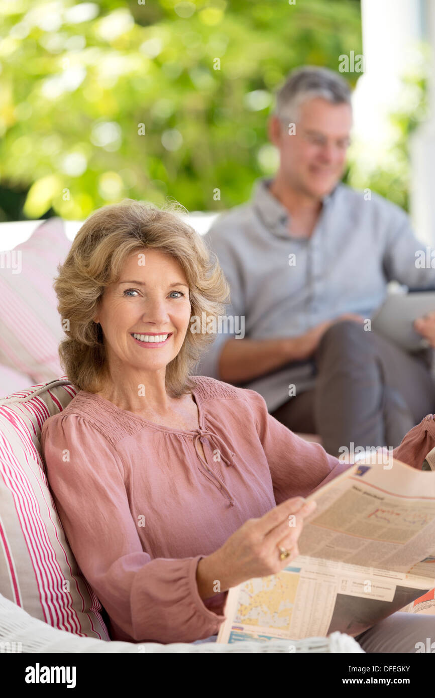 Portrait of senior woman reading newspaper on patio Banque D'Images