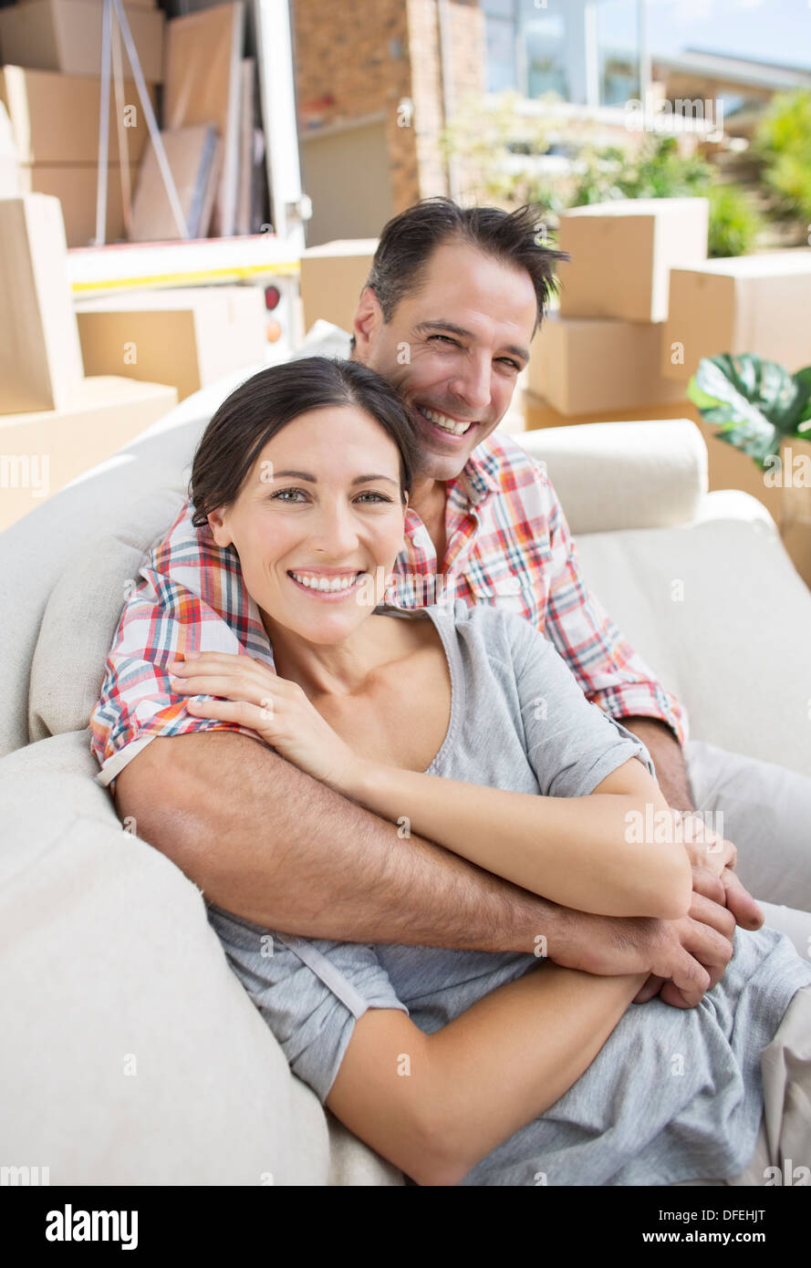 Portrait of smiling couple sitting on sofa in driveway près de camion de déménagement Banque D'Images