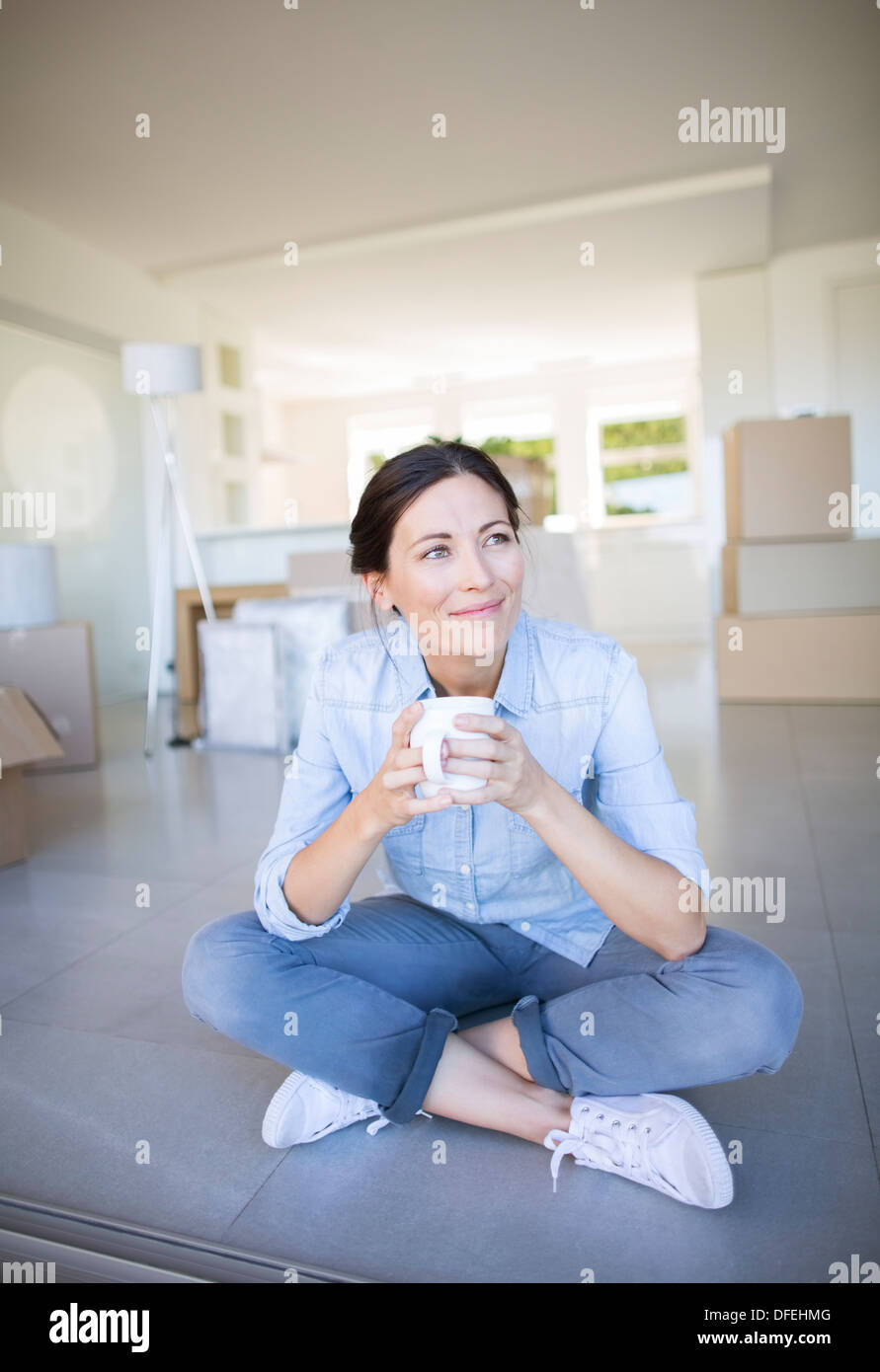 Happy woman enjoying coffee parmi les boîtes de carton Banque D'Images