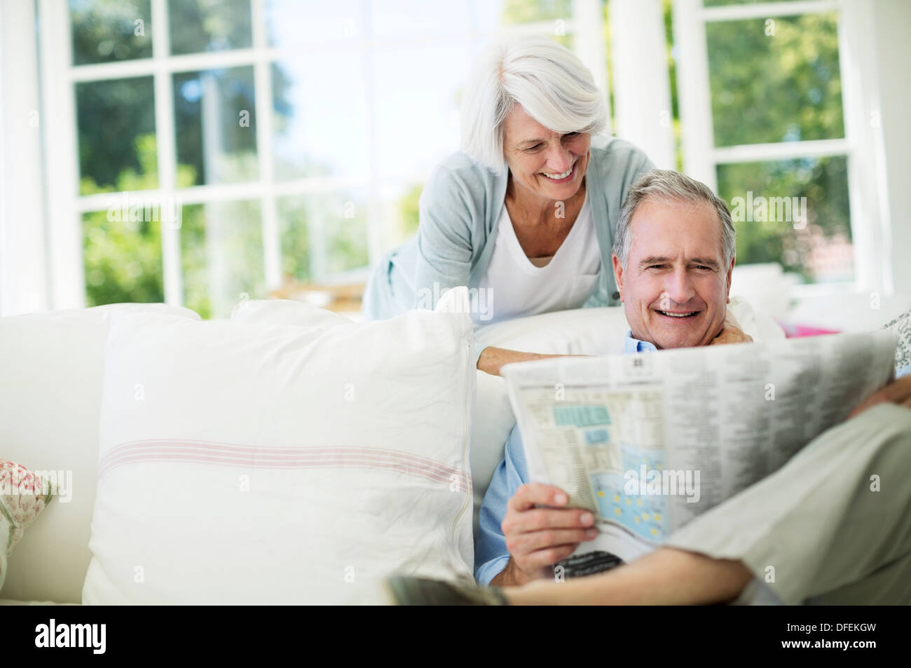 Senior couple reading newspaper on sofa Banque D'Images