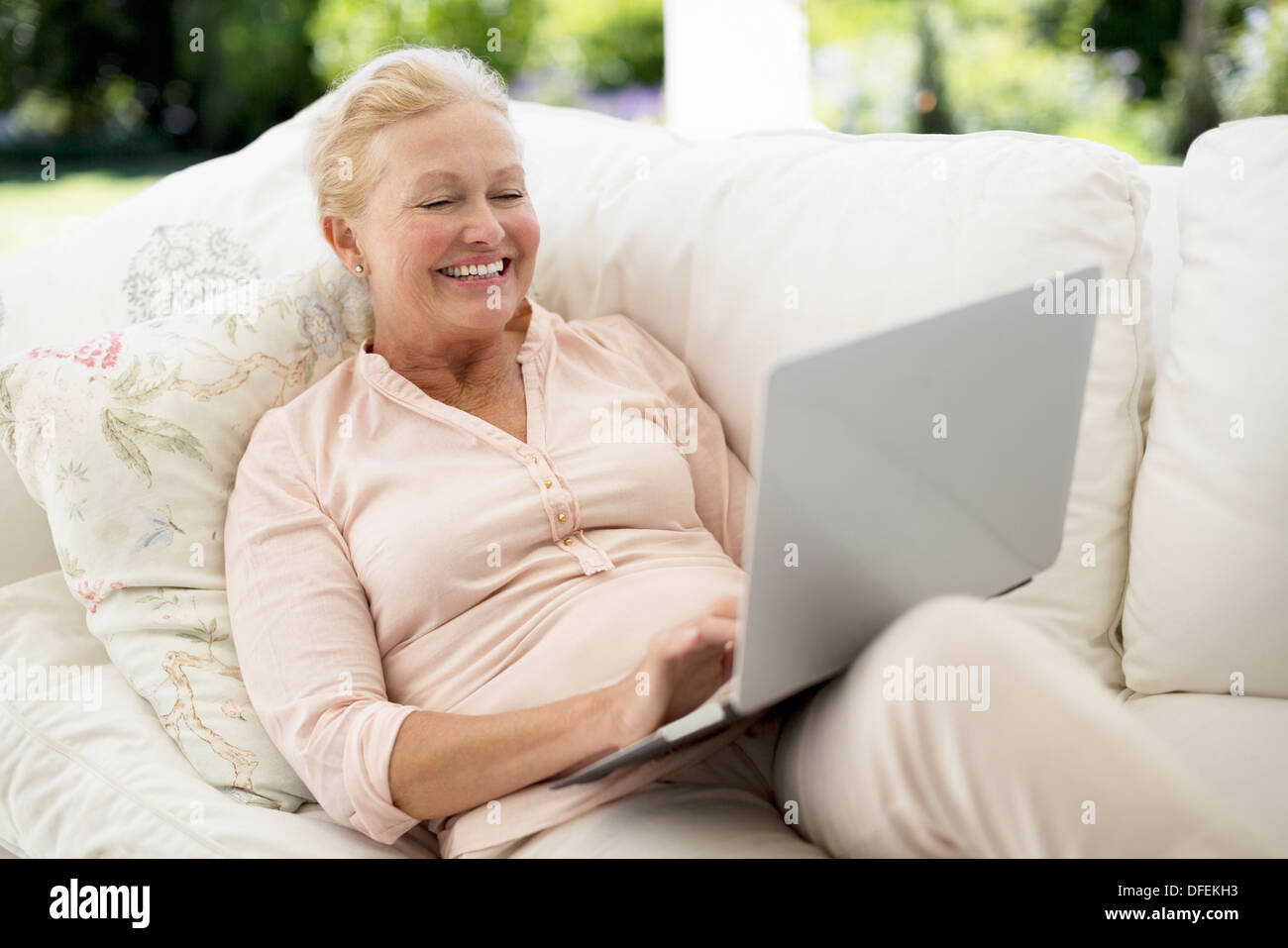 Senior woman using laptop on sofa Banque D'Images