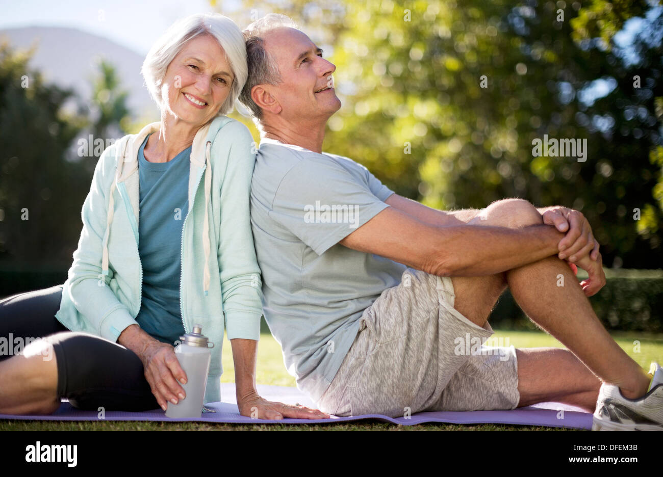 Senior couple sitting on yoga mat in park Banque D'Images