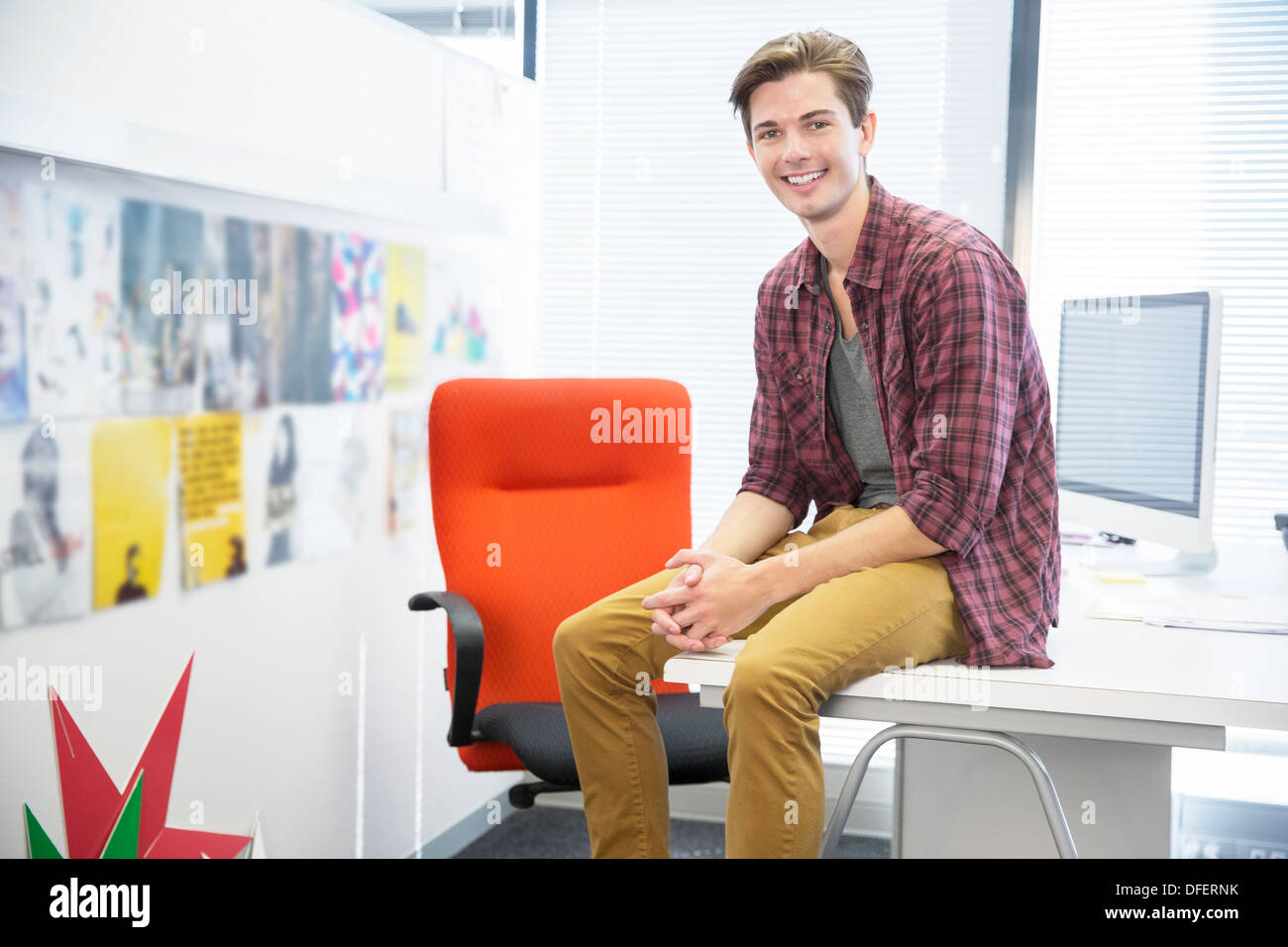 Businessman sitting on desk in office Banque D'Images