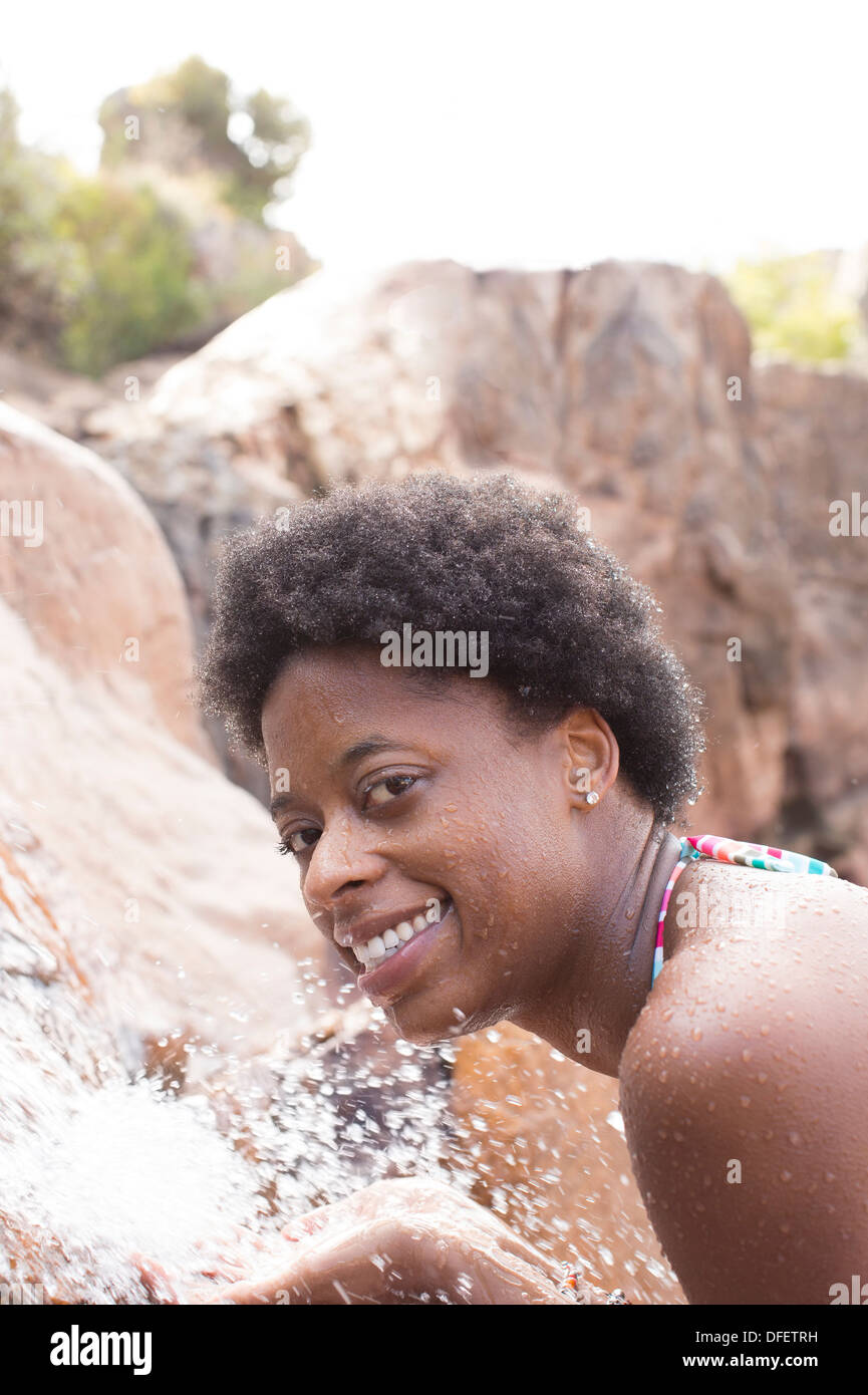 Portrait of smiling woman at waterfall Banque D'Images