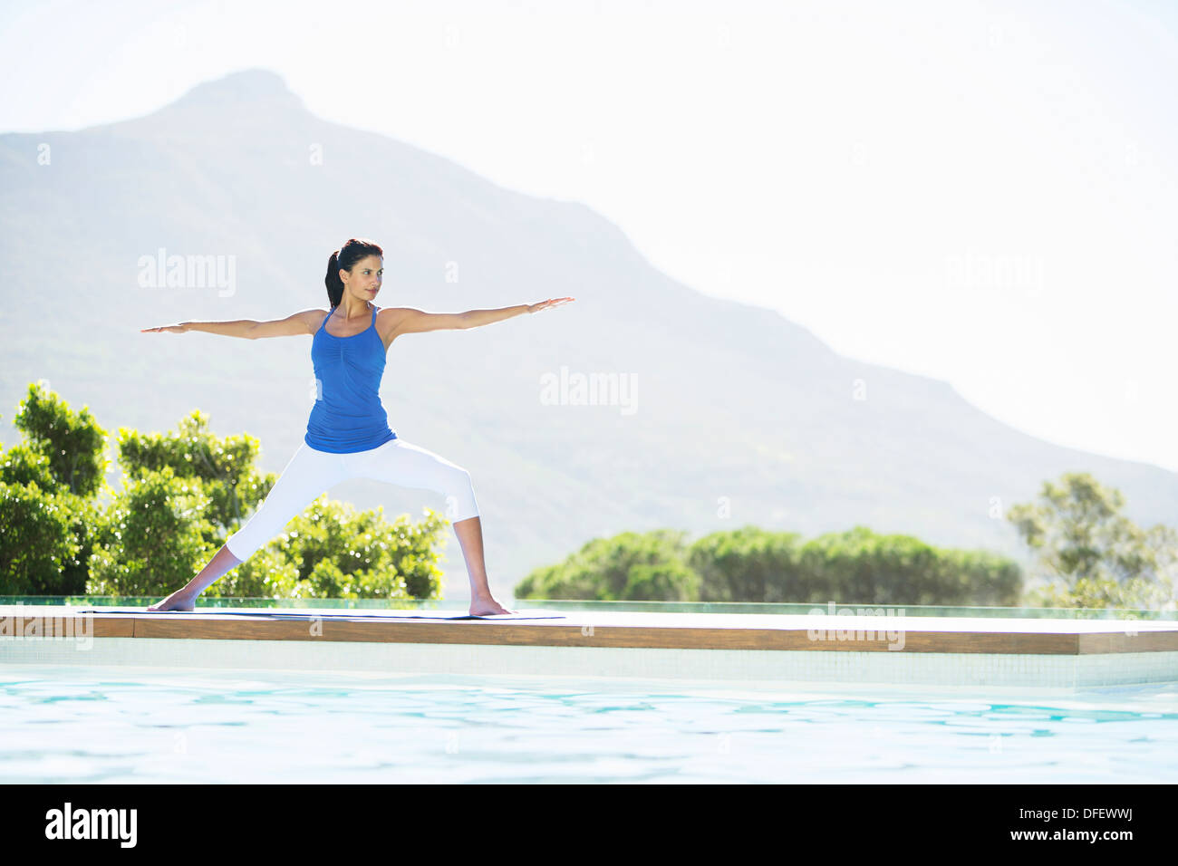 Woman practicing yoga at poolside Banque D'Images