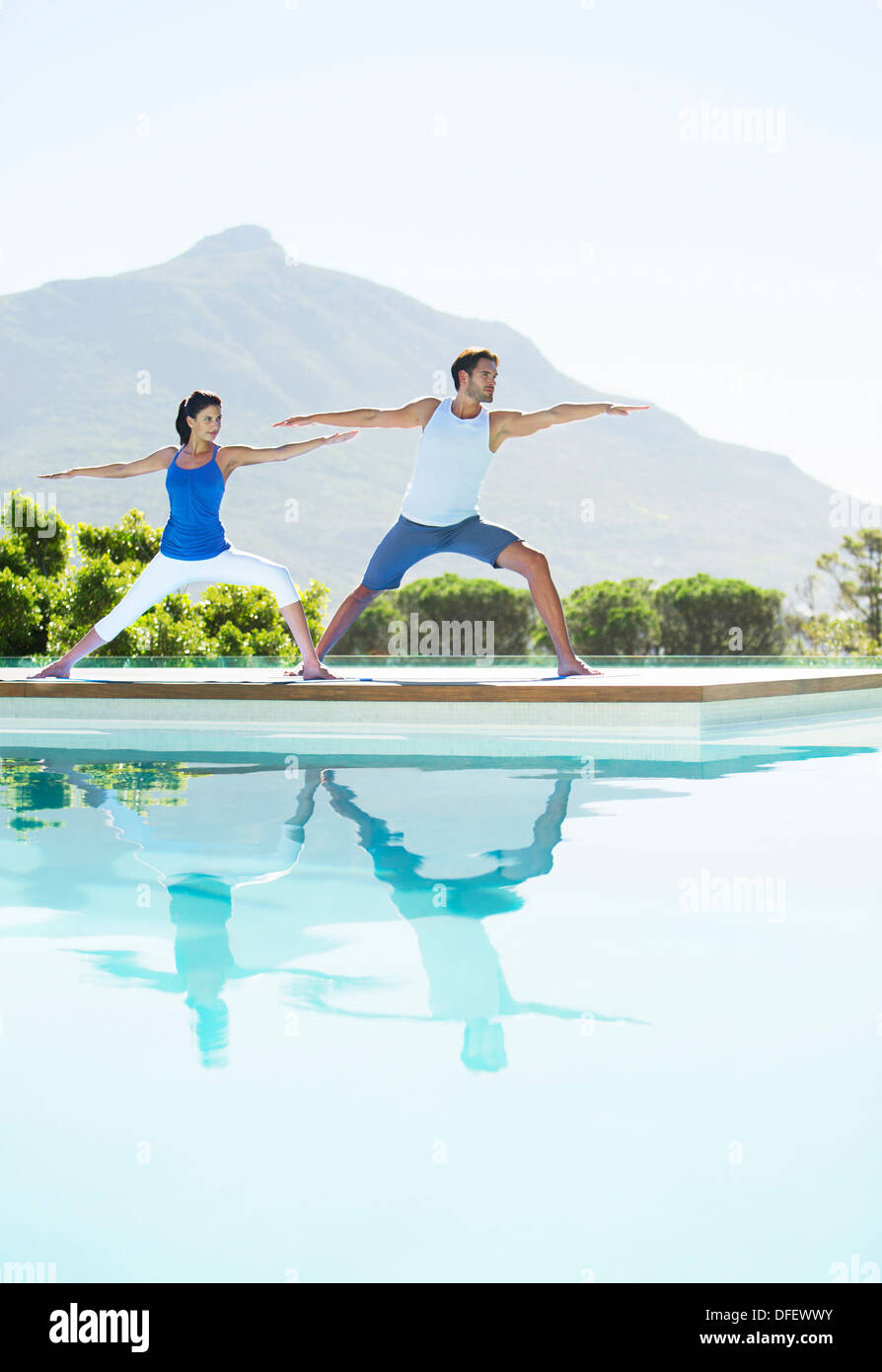 Couple practicing yoga at poolside Banque D'Images