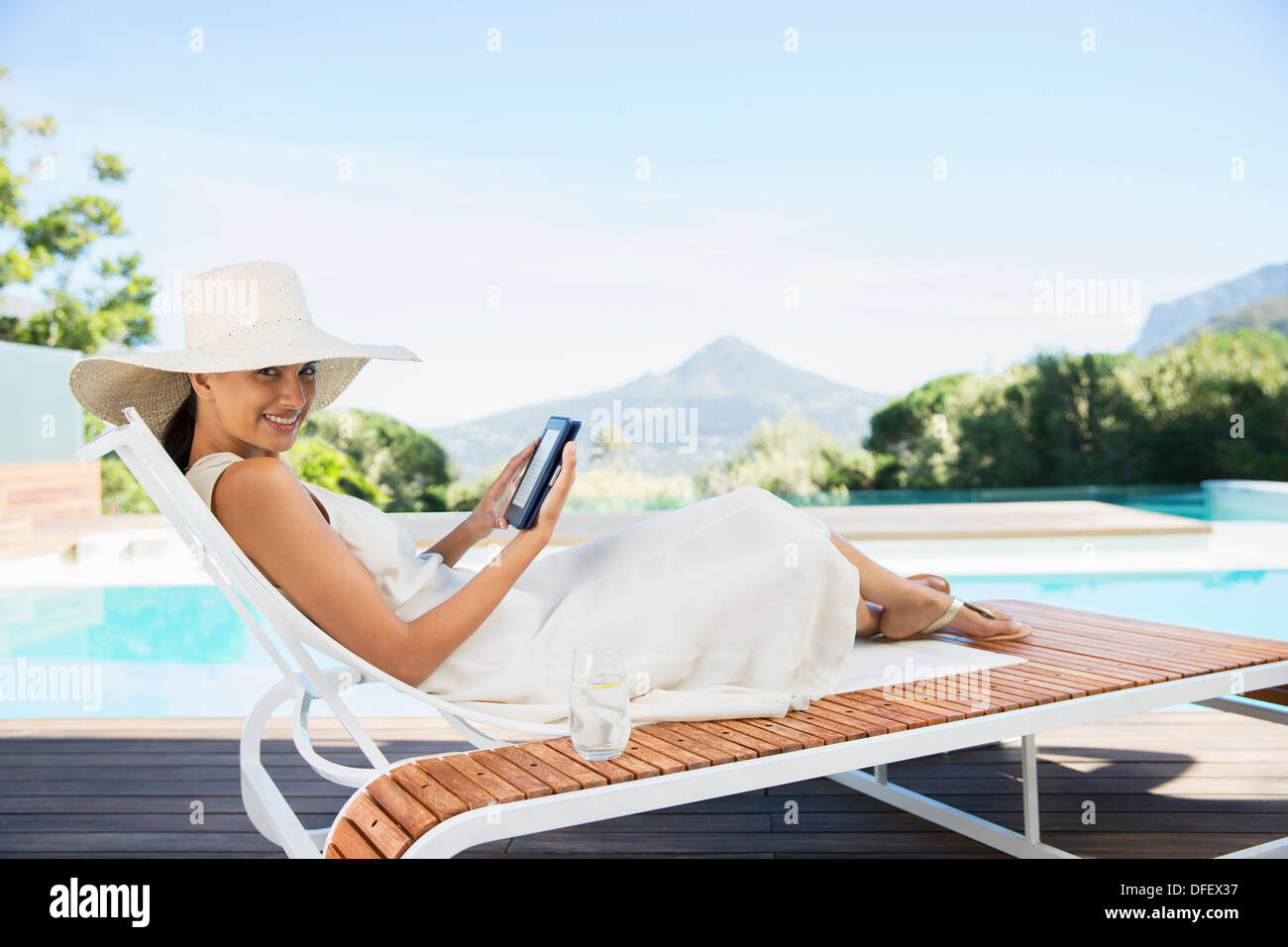 Woman using digital tablet on lounge chair at poolside Banque D'Images