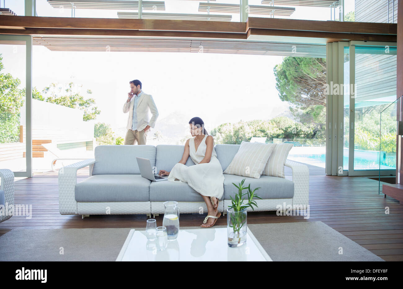 Couple using cell phone in living room Banque D'Images