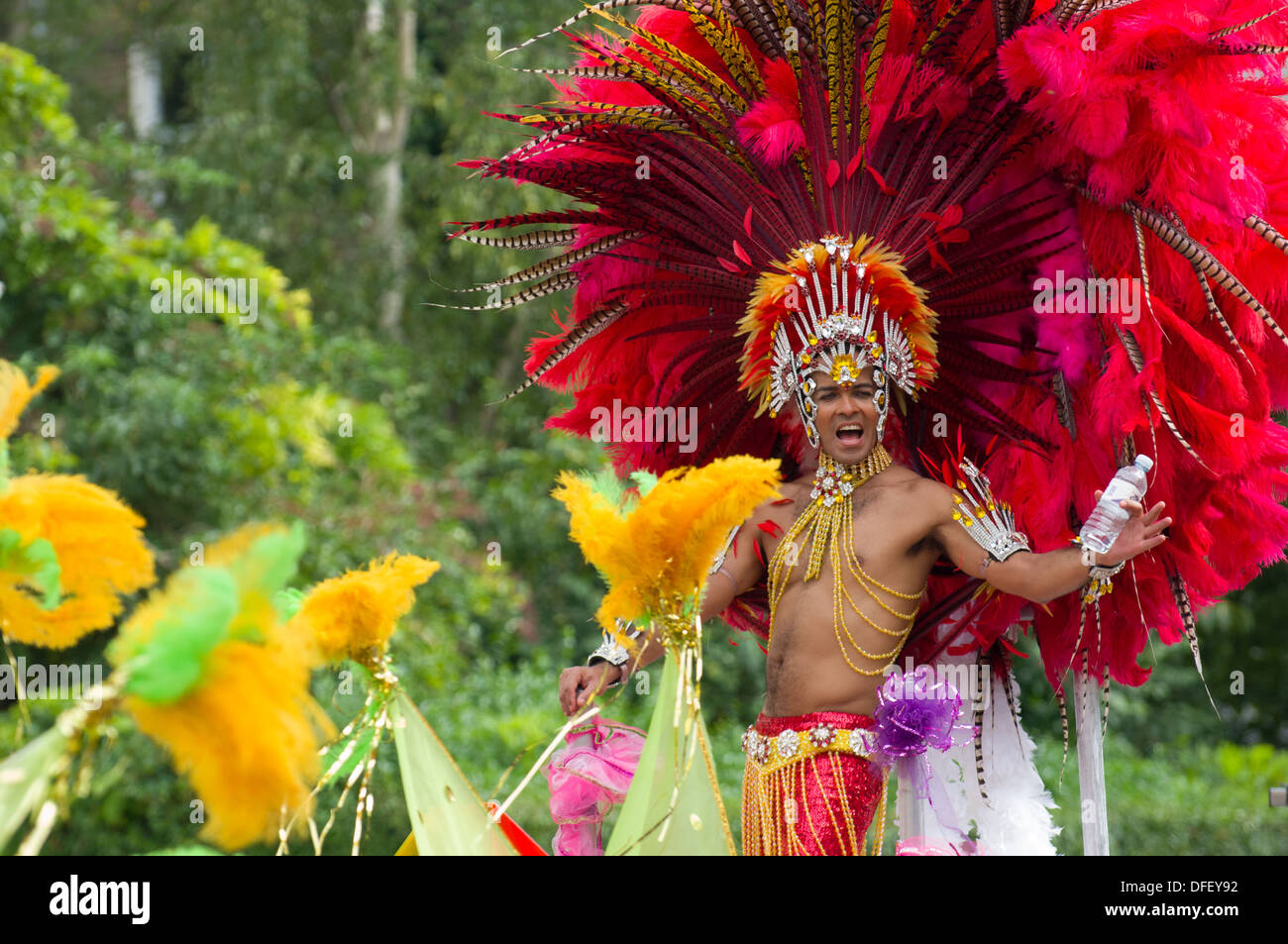 Carnaval d'hommes portant une coiffe élaborée interprète de plumes rouges sur un flotteur dans la procession, le carnaval de Notting Hill, Londres, Angleterre, Royaume-Uni Banque D'Images