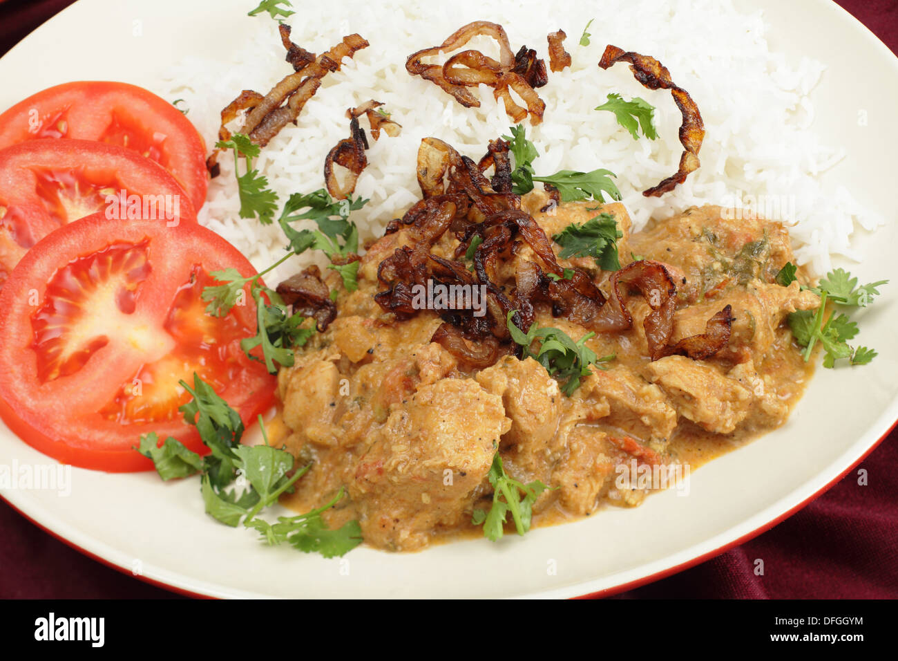 Sud-indien Poulet Korma, incoporating, noix de coco avec du riz basmati cuit et les feuilles de coriandre, oignons frits et de tranches de tomate. Banque D'Images