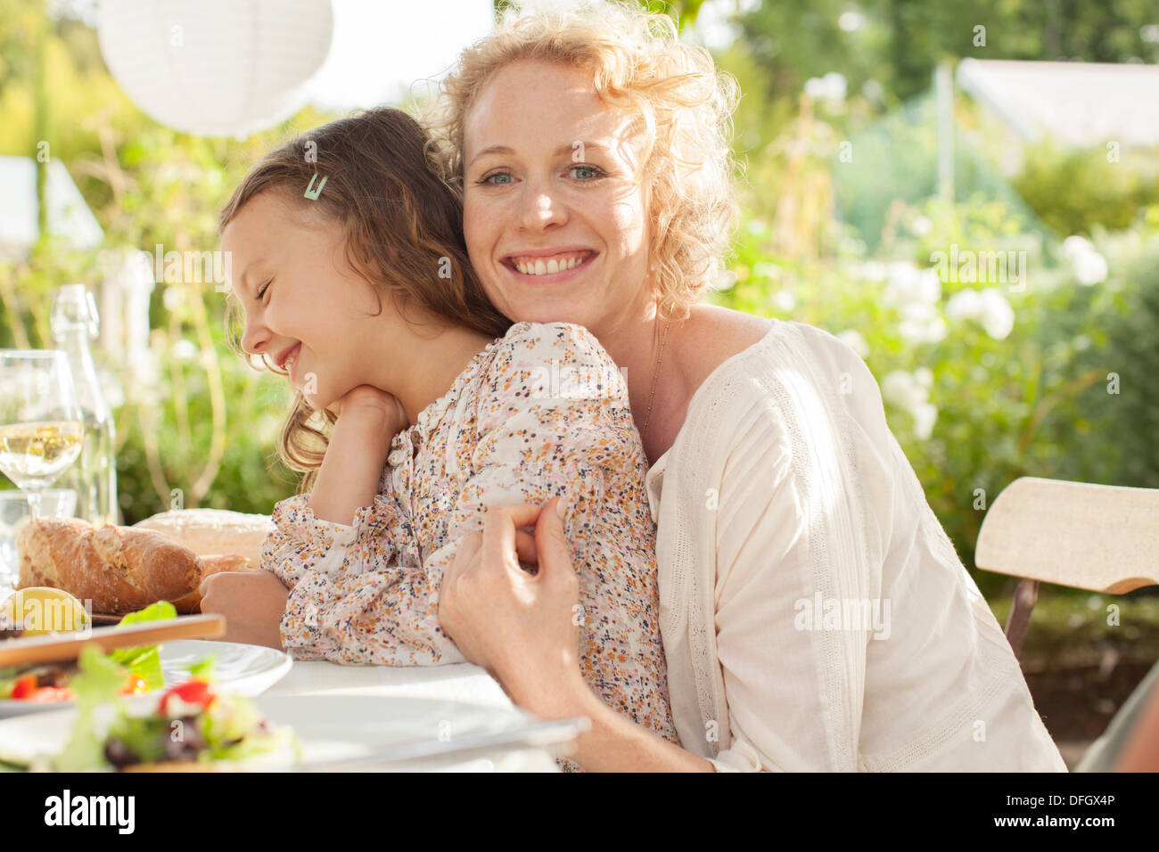 Mère et fille smiling at table outdoors Banque D'Images