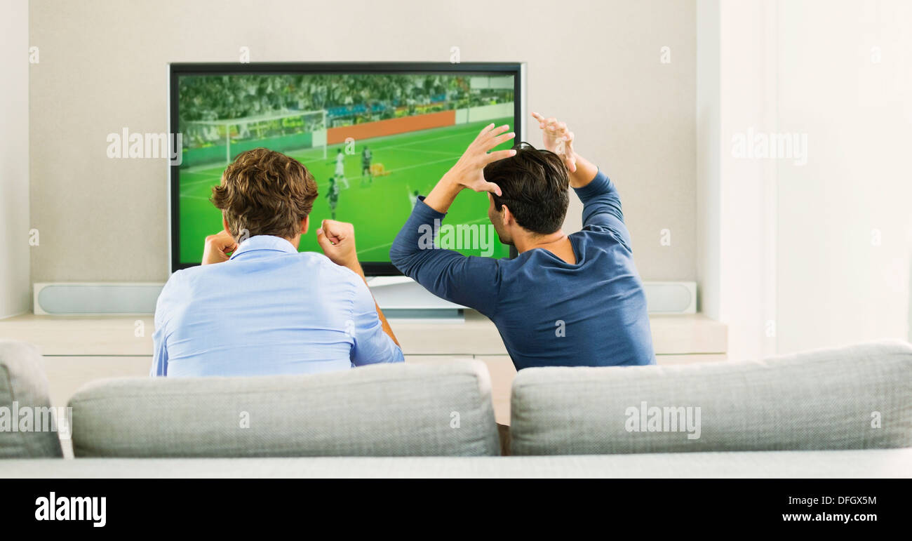 Les hommes regarder le soccer jeu sur canapé Banque D'Images