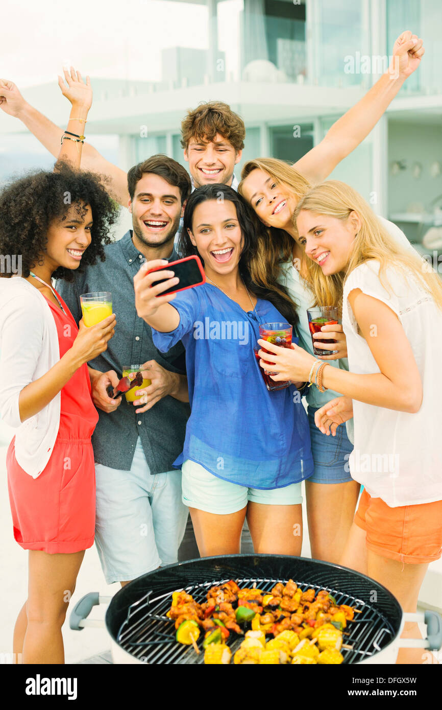 Friends taking self-portrait with camera phone at barbecue Banque D'Images